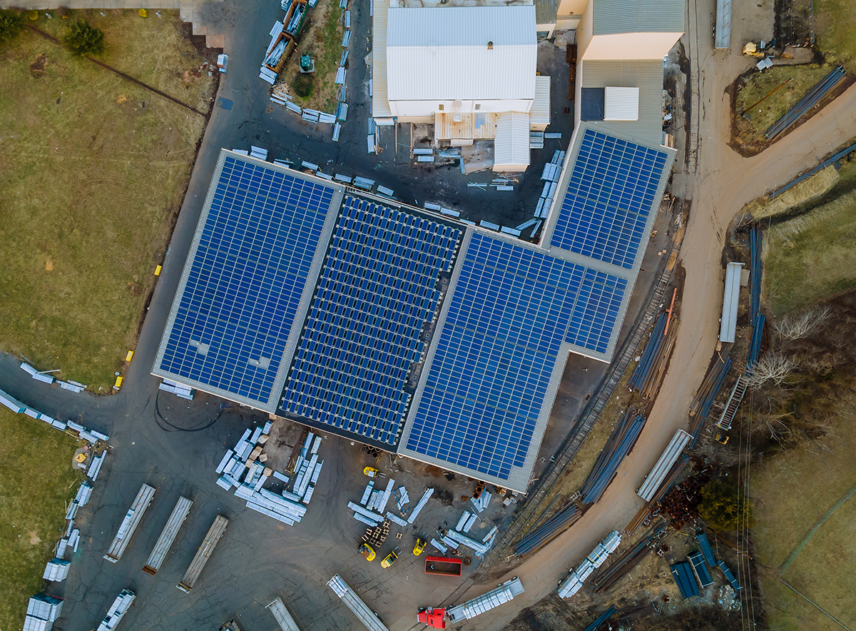 Solar panels installed on a roof of a large industrial a warehouse building.