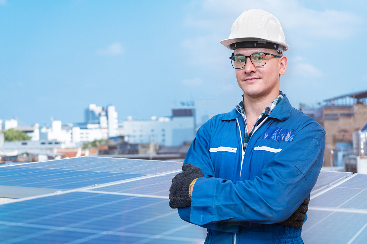 Portrait of engineer man worker is standing with confident at construction of solar cell panel or photovoltaic. Industrial Renewable energy. factory worker working on tower roof and skyscrapercity.